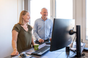 Freddy Munk Larsen and Carina Tranum standing in front of a computer at the ProAssign office.